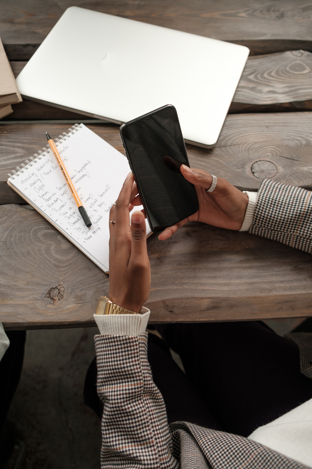 Woman Using Smartphone While Writing Notes
